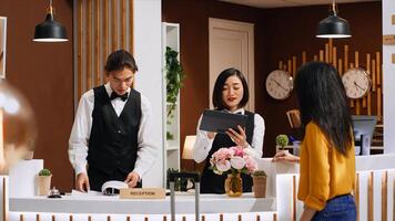 Hotel guest signing for room registration on tablet at front desk, finishing check in process and preparing to see room. Asian traveler filling in reports and forms to ensure pleasant stay at resort. photo