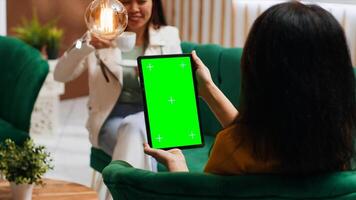 Woman tourist looking at tablet with greenscreen display in hotel lobby, checking isolated mockup template on modern wireless gadget. Guest with chromakey on device in lounge area. photo