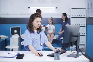 caucásico hembra enfermero utilizando el computadora escritorio, a verificar paciente información y equipo, mientras masculino médico ayuda madre y hija. un escena de cuidado de la salud y comunicación. foto