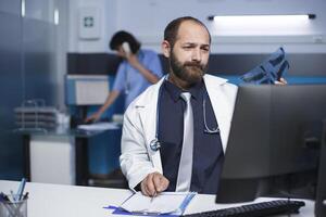 detallado Disparo de un blanco médico escritura en un cuaderno mientras examinando un radiografía cofre imagen de un paciente. un chico en un laboratorio Saco es visto arriba cerca manejo y inspeccionando un del paciente cofre escanear. foto