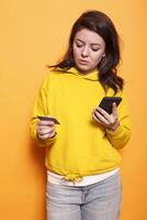 Woman using smartphone to shop online is having problems inputting credit card information. Young female person using a mobile phone to order products while holding her bank card. photo