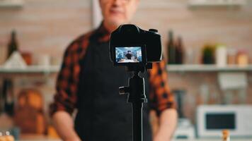 Baker presenting how using wheat flour while recording video tutorial. Retired blogger chef influencer using internet technology communicating, shooting blogging on social media with digital equipment photo