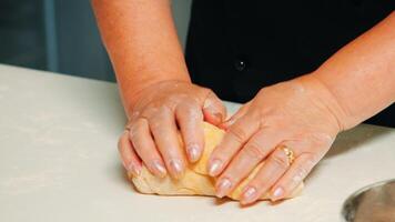 Close up of hands taking a large piece of pastry, making buns from dough. Retired elderly baker with bonete mixing ingredients with sifted wheat flour kneading for baking traditional cake and bread. photo