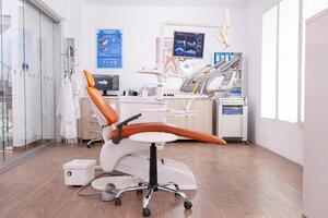 Empty professional stomatology hospital office room with nobody in it equipped with modern orthodontic furniture. Teeth radiography images on monitor revealing tooth dental medical diagnosis photo