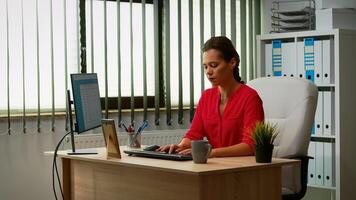 Busy employee typing on computer sitting on chair in modern office. Entrepreneur working in modern professional office, workplace in personal company typing on computer keyboard looking at desktop photo