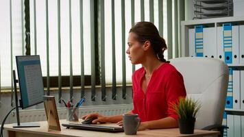 Hispanic lady working in modern office early in the morning. Entrepreneur comming at work, in professional workspace, workplace in personal company typing on computer keyboard looking at desktop photo