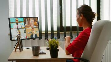 Woman talking with colleagues about project on video call. Freelancer working with business remotely team discussing chatting having virtual online conference meeting webinar using internet technology photo