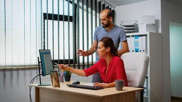 Team searching the best solution in front of computer in modern office room. Coworkers discussing working in workplace in personal corporate company typing on pc keyboard pointing at desktop photo