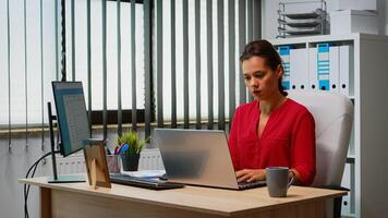 Businesswoman working at laptop and computer in same time. Entrepreneur sitting in modern professional office, workplace in personal corporate company typing on computer keyboard looking at desktop photo