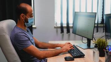 Freelancer typing on computer and cleaning hands with alcohol. Entrepreneur working in new normal office workplace in company disinfecting hands using antibacterian gel against corona virus. photo