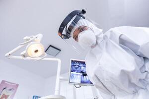 Dentist point of view wearing protection gear against covid outbreak during treatment in dental office. Stomatolog wearing safety gear against coronavirus during heatlhcare check of patient. photo