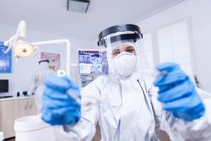 pov de paciente consiguiendo dental tratamiento en dentista oficina estomatólogo vistiendo la seguridad engranaje en contra coronavirus durante cuidado del calor cheque de paciente. foto