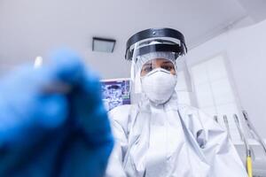 First person view of dentist preparing for teeth examination in hazmat suit agasint covid. Stomatolog wearing safety gear against coronavirus during heatlhcare check of patient. photo