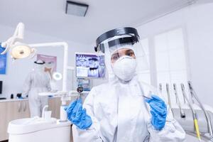 paciente pov de dentista y asistente en trabajando en boca hygine en traje contra COVID-19. estomatólogo vistiendo la seguridad engranaje en contra coronavirus durante cuidado del calor cheque de paciente. foto