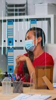 Woman with protection mask having online meeting conference in modern new normal office. Freelancer working in workplace chatting with remotely team during virtual webinar using internet technology photo