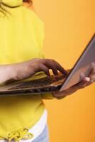 Close-up of caucasian individual typing on digital laptop in front of isolated background. Detailed view of female person using online technology on wireless computer to browse on website network. photo