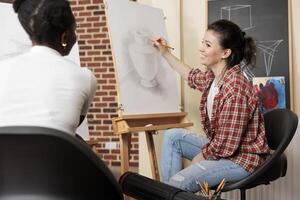 Two diverse girls best friends enjoying creative activities together, having enjoyable experience at art workshop, taking drawing class together. People enjoying creative hobby, learning something new photo