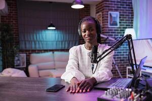 retrato de africano americano Internet celebridad radiodifusión En Vivo en transmisión plataforma utilizando profesional micrófono productor alto calidad producción. mujer creando en línea contenido para su aficionados foto