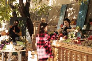 Person talking to seller and choosing apples at local farm market, standing near fruits and vegetables in boxes on bio stall. Farmer selling organic products to customer at seasonal greenmarket. photo