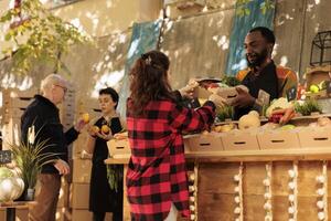 Farmers market vendor giving fresh organic produce box to customer, natural bio products. Woman buying healthy locally grown fruits and vegetables at roadside stand, small business. photo