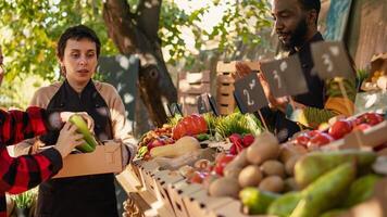 Senior man and young woman buying organic bio products, visiting local farmers market stand. Smiling vendors greeting customers and selling homegrown fruits and veggies from farm. photo