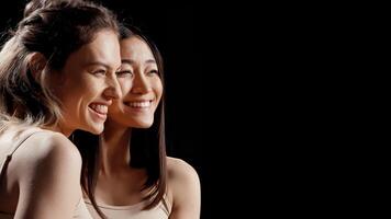 Diverse happy girls hugging each other in beauty ad, feeling flawless and cheerful about skincare campaign. Two beautiful women posing on camera promoting body acceptance and diversity. photo