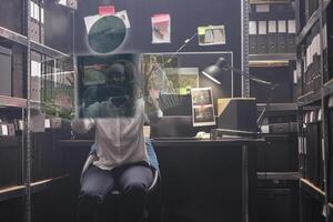 joven mujer policía mirando a pistas en holograma, examinando aumentado realidad holográfico fotos a resolver delito en policía archivo habitación. privado detective trabajando con artificial inteligencia.