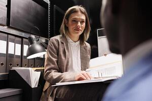 Managers organizing at business files, analyzing bureaucracy record in storage room. Diverse businesspeople discussing accountancy report, checking administrative documents in corporate depository photo