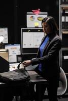 Businesswoman packing laptop up in office suitcase bag clocking out from storage room office. Bookkeeping asian executive in business accountancy company file cabinet depository photo