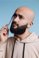 Young thoughtful arabian man rubbing head with pan while making decision and looking away. Puzzled person thinking, planning and dreaming with uncertain facial expression photo