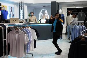 Cheerful smiling shopaholic dancing after making successful purchase in clothing store. Fashion boutique satisfied asian woman customer holding shopping bags in department mall photo