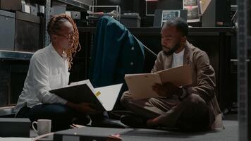 African american detectives team working in archive to solve criminal case, analyzing forensic evidence in incident room. Man and woman discussing about insight and statements. Handheld shot. photo