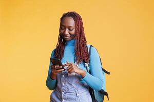 Happy girl using mobile phone app, looking at online internet map and browsing website in studio. Excited young adult travelling on international vacation journey, voyage destination. photo