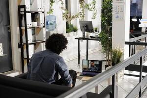 Employee discussing project strategy with executive manager during virtual conference in corporate workspace. Start up company worker talking with client on laptop screen in business office photo