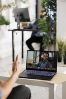 Executive on laptop screen listening to employee presentation through video call. Project manager having online meeting with african american colleague in coworking space photo