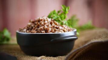 buckwheat boiled in a ceramic bowl on a wooden table. video