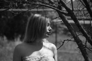 Black and white photo, girl in the garden on a meadow in a dress. photo