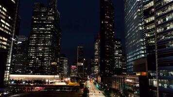 Singapur - agosto, 2018. noche con hermosa ciudad en luces siguiente a eso es ocupado carretera. disparo. parte superior ver Entre rascacielos de empresa con iluminado ventanas en noche. concepto de la vida nocturna en video