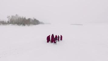 Religion procession. Footage. Group of monks in hood robe walking along winter snow trail video