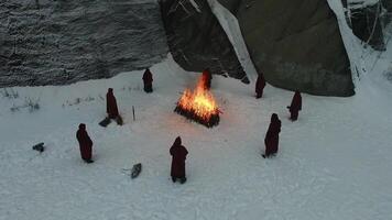 gruppo di incappucciato di il fuoco nel il montagne. filmato. il scena di il sacrificio nel il montagne nel inverno. religioso rituale di sacrificio di aggiunta video