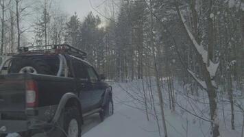 coche paseos en un invierno bosque la carretera. un coche en un cubierto de nieve la carretera entre arboles video