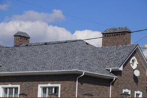Asphalt shingle. Decorative bitumen shingles on the roof of a brick house. photo