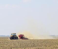 Tractor rides on the field and makes the fertilizer into the soi photo