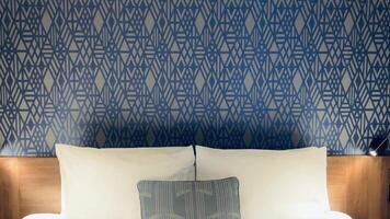 modern hotell rum, samtida konst deco design, med en geometrisk mönstrad tapet och säng med en dekorativ kudde video