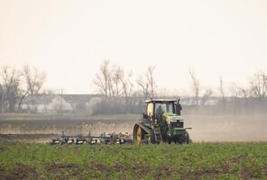 Tractor plowing the soil processes photo