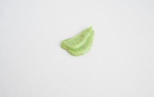 A sample of a natural green scrub on a white background. Peeling cream with microcapsules. Smear of apple or coffee scrub. photo