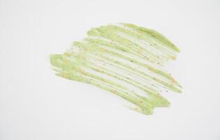 A sample of a natural green scrub on a white background. Peeling cream with microcapsules. Smear of apple or coffee scrub photo