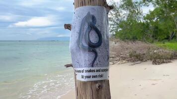 pas op van slangen en schorpioenen waarschuwing teken Aan een tropisch strand, met Doorzichtig zee en lucht achtergrond, markeren veiligheid maatregelen in exotisch reizen bestemmingen video
