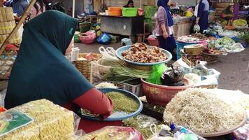 lombok, Indonesia - 31 diciembre 2023. vegetal vendedor a un tradicional mercado quien es limpieza brote vegetales con tradicional herramientas video