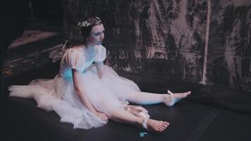 een ballerina strekt zich uit haar poten terwijl zittend achter de schermen en op zoek Bij de fase. de ballet danser is voorbereidingen treffen voor een prestatie. professioneel ballet. video